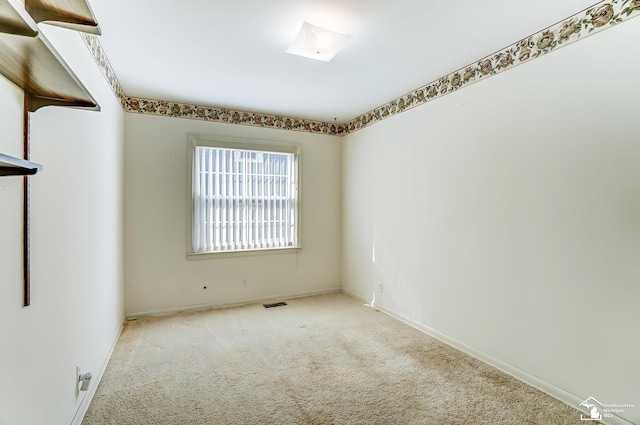 unfurnished room with baseboards, visible vents, and light colored carpet