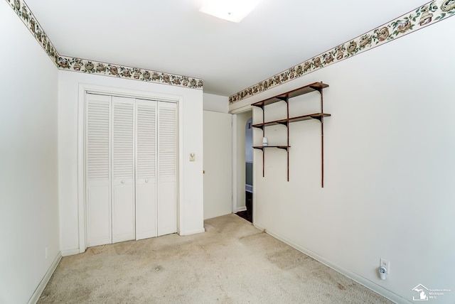 unfurnished bedroom with a closet and light colored carpet