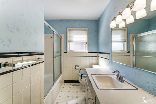 bathroom with wainscoting, a healthy amount of sunlight, toilet, and wallpapered walls