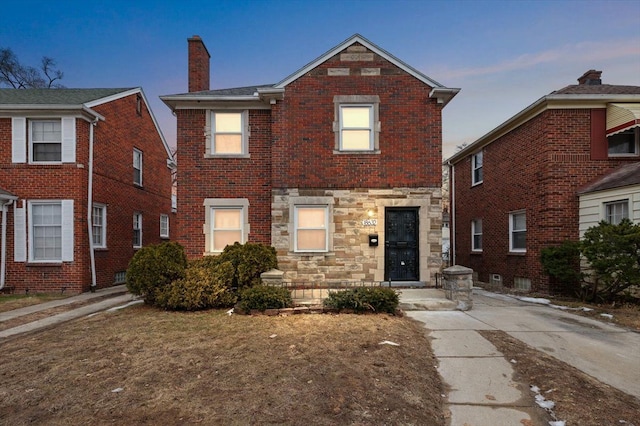 view of front of house featuring stone siding, a chimney, and brick siding