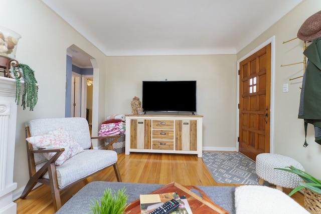 living area featuring arched walkways, baseboards, and wood finished floors