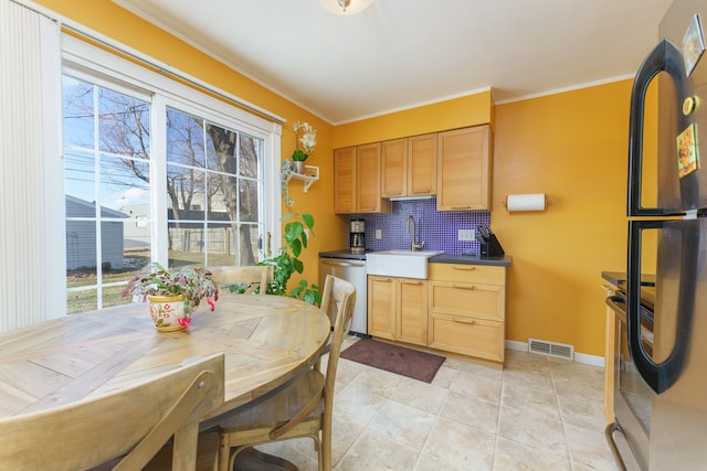 kitchen featuring a sink, visible vents, freestanding refrigerator, dishwasher, and tasteful backsplash