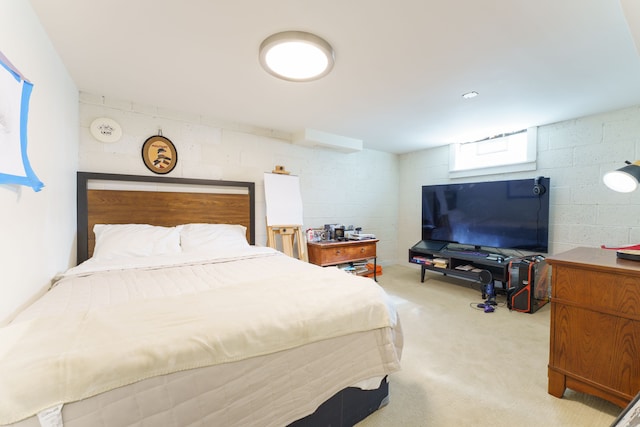 bedroom featuring concrete block wall and light colored carpet