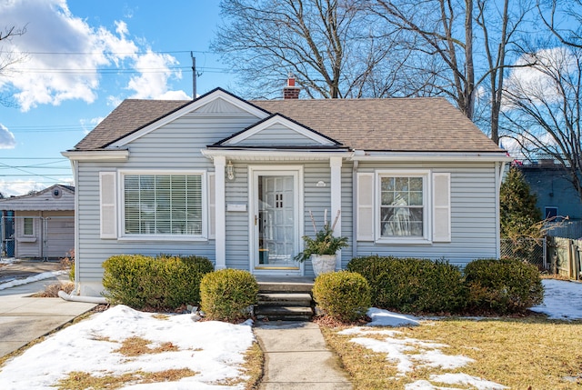 bungalow featuring a chimney and roof with shingles