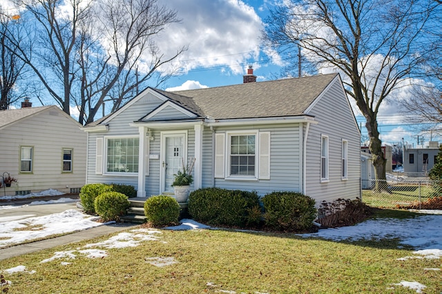 bungalow featuring a shingled roof, a front yard, fence, and a chimney