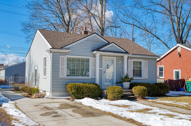 bungalow featuring a shingled roof, fence, and a chimney