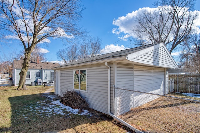 view of side of home featuring a garage, fence, a lawn, and an outbuilding