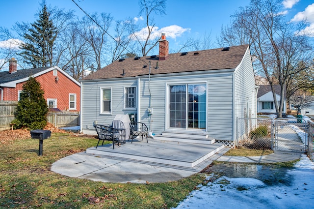 rear view of property with entry steps, a chimney, roof with shingles, fence, and a yard