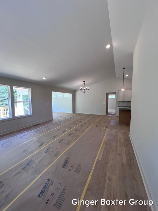 1910 Fallasburg Park Dr NE Unit 5, Lowell, MI 49331 - unfurnished living room with wood finished floors, healthy amount of natural light, lofted ceiling, baseboards, and a chandelier