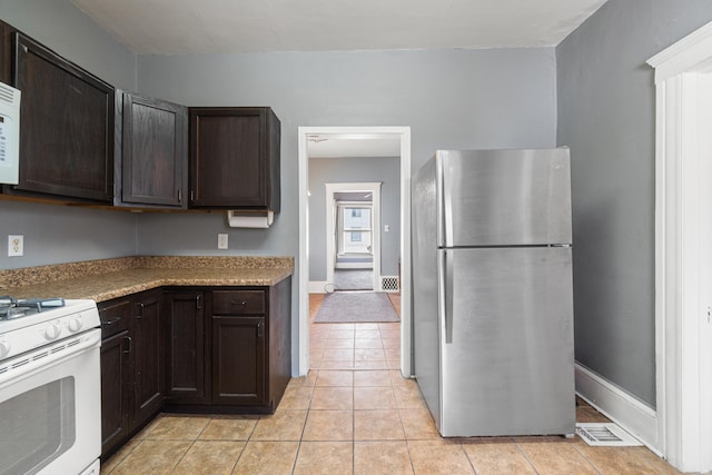 kitchen featuring white appliances, light countertops, dark brown cabinets, and light tile patterned floors