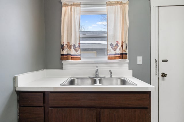 kitchen featuring light countertops, a sink, and dark brown cabinetry