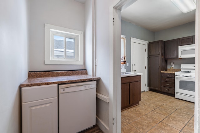 kitchen with dark countertops, white appliances, light tile patterned flooring, and dark brown cabinetry