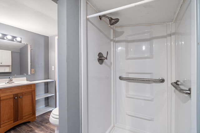 bathroom featuring a stall shower, vanity, toilet, and wood finished floors