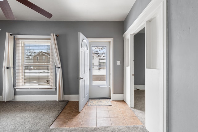 foyer featuring light carpet, light tile patterned floors, baseboards, and a ceiling fan