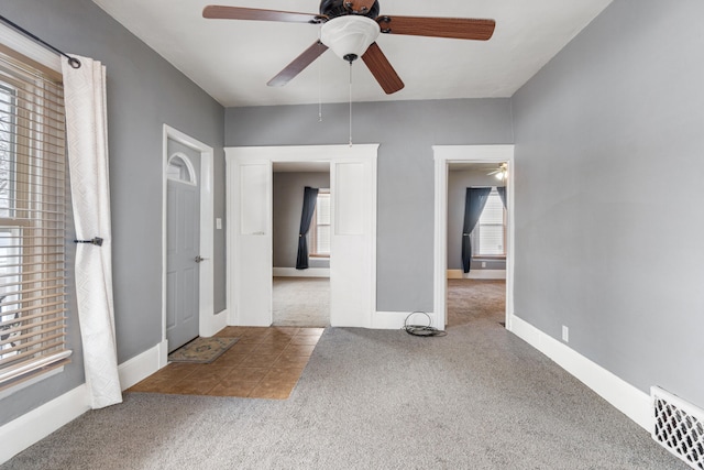 tiled empty room with baseboards, visible vents, and carpet flooring