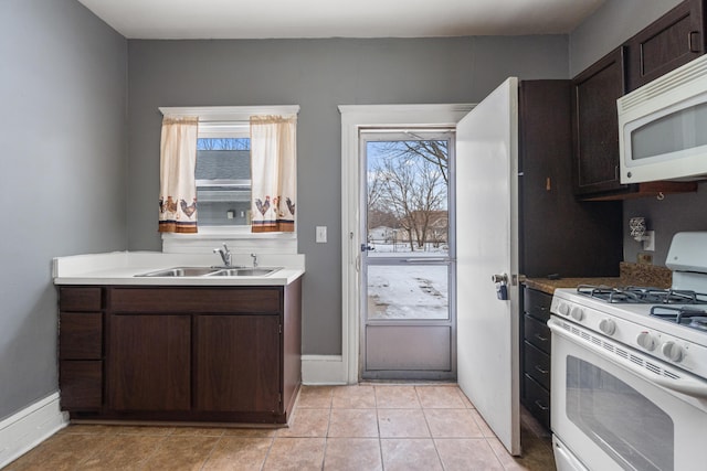 kitchen with white appliances, light tile patterned floors, light countertops, dark brown cabinets, and a sink