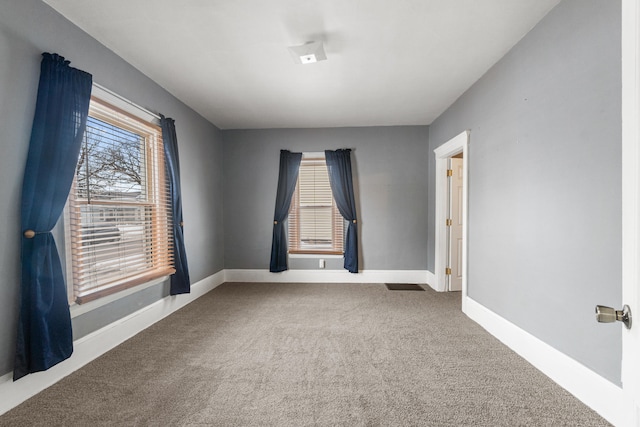 spare room featuring carpet floors and baseboards