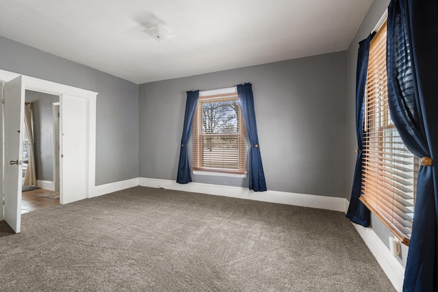 empty room featuring carpet and baseboards