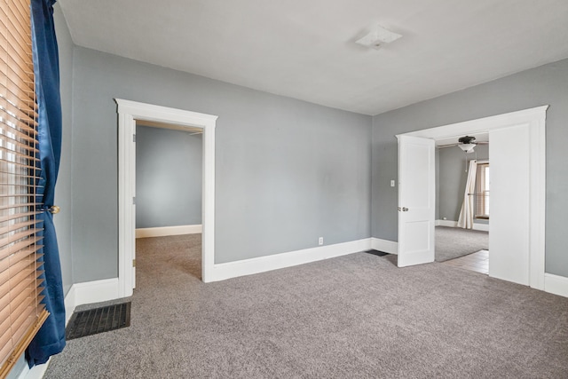 carpeted empty room featuring baseboards and visible vents