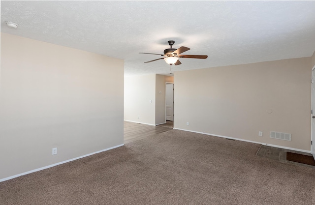 carpeted empty room featuring a textured ceiling, ceiling fan, visible vents, and baseboards