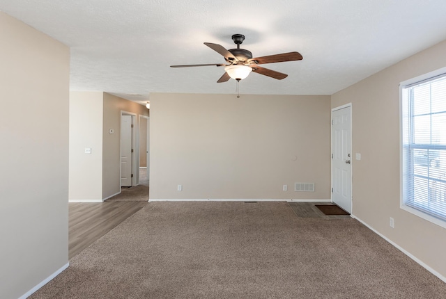 unfurnished room with visible vents, ceiling fan, light carpet, and baseboards