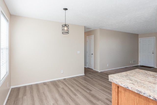 interior space with baseboards, light wood-style floors, and a healthy amount of sunlight