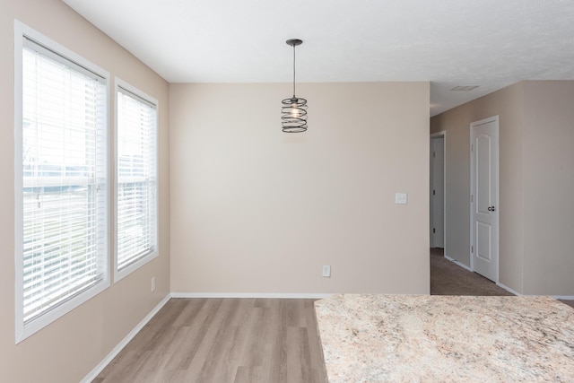 unfurnished room with a healthy amount of sunlight, visible vents, baseboards, and wood finished floors