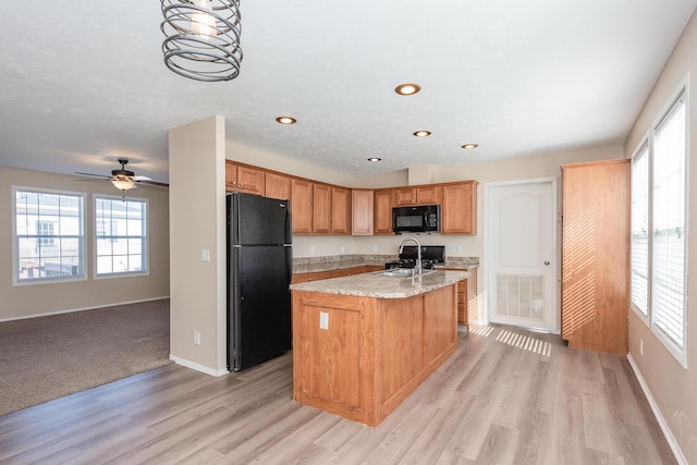 kitchen with a kitchen island with sink, a sink, visible vents, a wealth of natural light, and black appliances