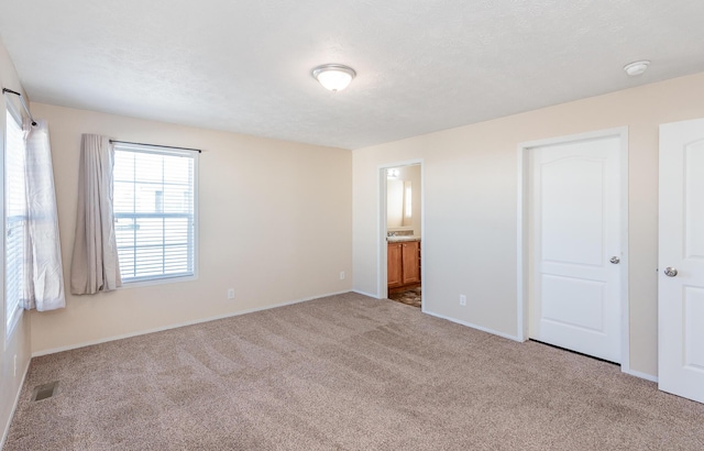 unfurnished bedroom featuring a textured ceiling, carpet floors, visible vents, and baseboards