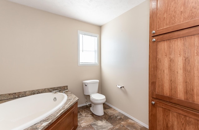 bathroom featuring stone finish flooring, a garden tub, toilet, and baseboards