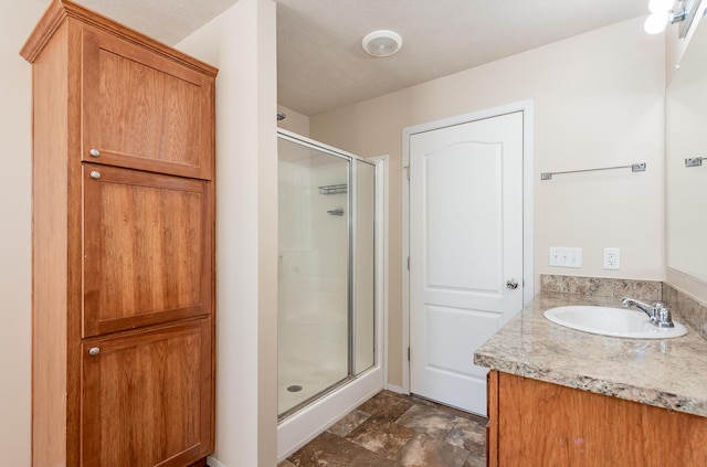 full bath with a stall shower, stone finish flooring, and vanity