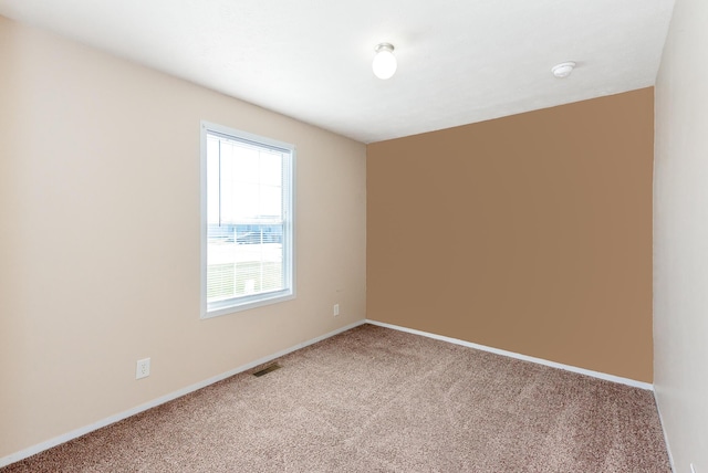 carpeted spare room with visible vents and baseboards