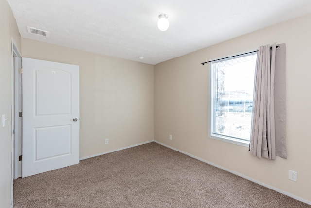 empty room with baseboards, visible vents, and carpet flooring