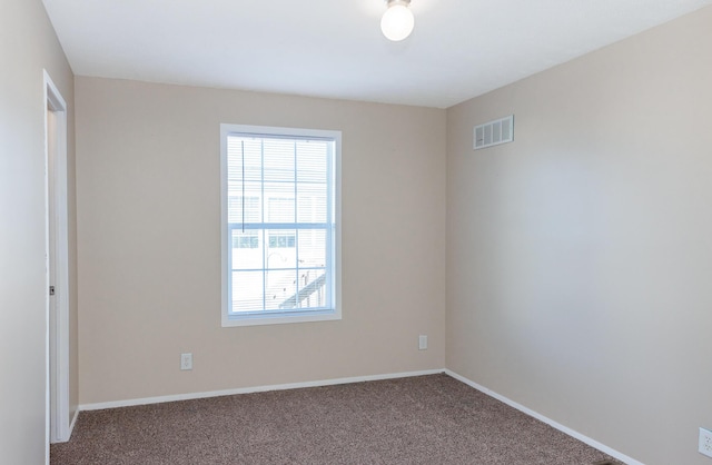 carpeted spare room featuring visible vents and baseboards