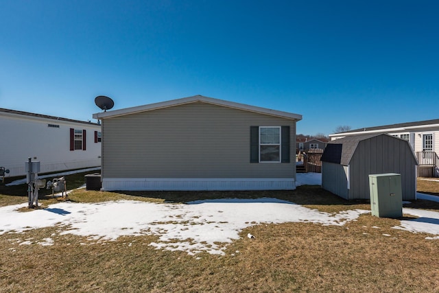 view of side of home with a storage shed, a yard, and an outbuilding