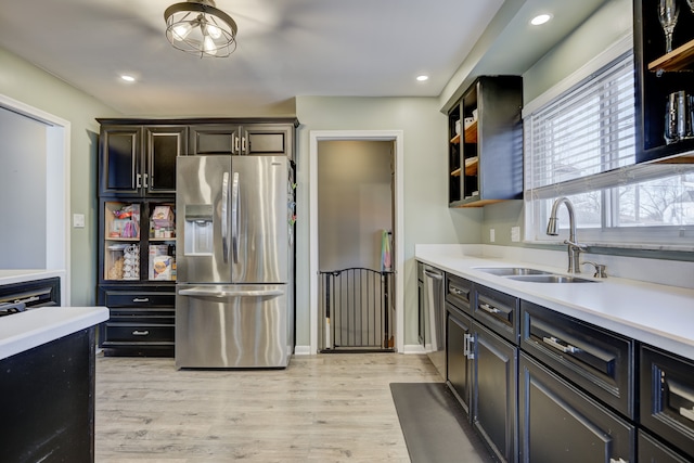 kitchen with open shelves, light countertops, appliances with stainless steel finishes, light wood-style floors, and a sink