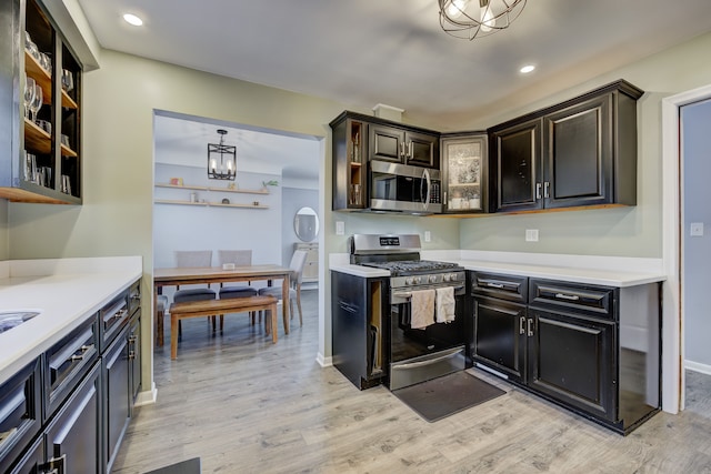 kitchen featuring stainless steel appliances, light countertops, glass insert cabinets, and light wood finished floors