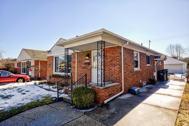 bungalow-style home featuring a garage, an outbuilding, and brick siding