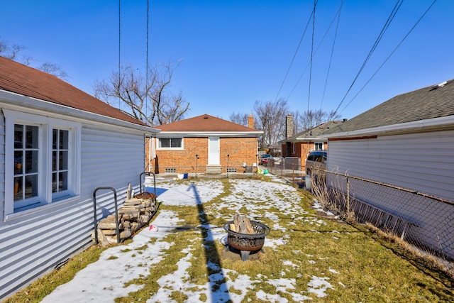 yard covered in snow featuring entry steps, an outdoor fire pit, and fence