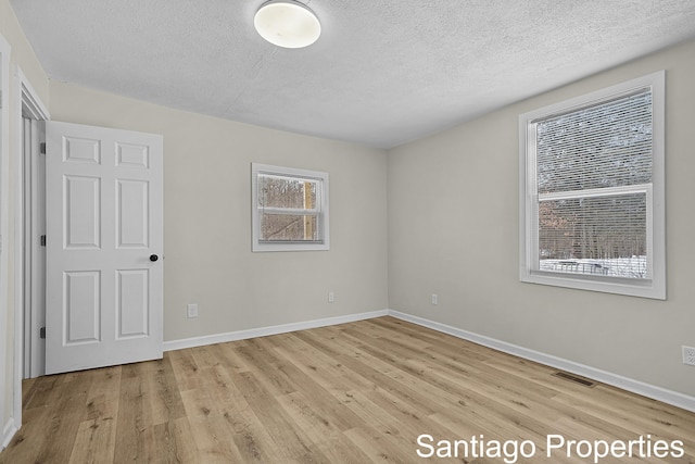 unfurnished bedroom with baseboards, visible vents, a textured ceiling, and light wood finished floors