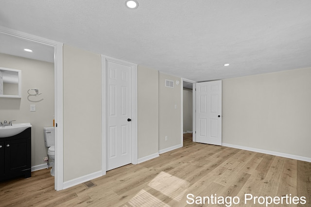 unfurnished bedroom with light wood finished floors, recessed lighting, visible vents, a textured ceiling, and baseboards