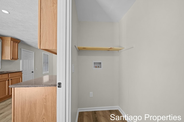 laundry room featuring hookup for a washing machine, light wood-style floors, a textured ceiling, laundry area, and baseboards