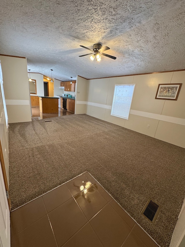 unfurnished living room featuring a textured ceiling, carpet floors, visible vents, and a ceiling fan