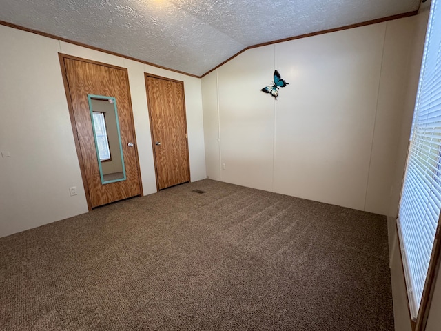 carpeted spare room featuring ornamental molding, vaulted ceiling, and a textured ceiling