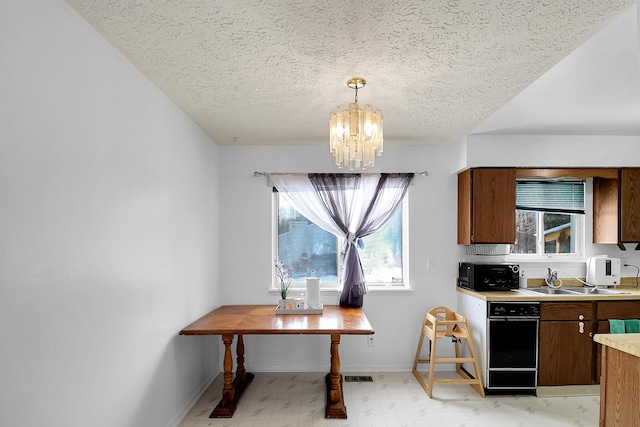 kitchen featuring a notable chandelier, light countertops, hanging light fixtures, visible vents, and a sink