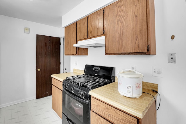 kitchen with under cabinet range hood, black range with gas stovetop, light countertops, and brown cabinetry