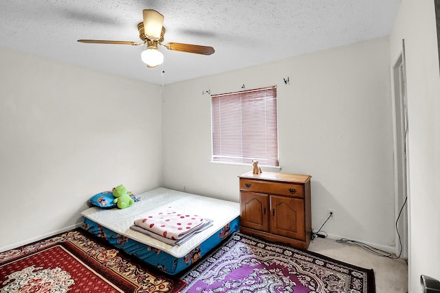 bedroom featuring light carpet, ceiling fan, and a textured ceiling