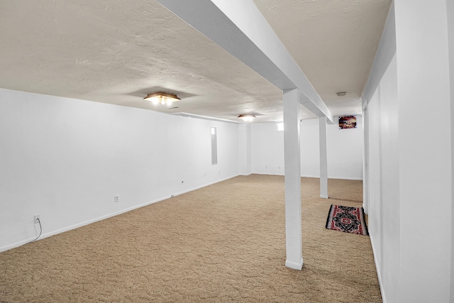 finished below grade area featuring a textured ceiling, carpet flooring, and baseboards