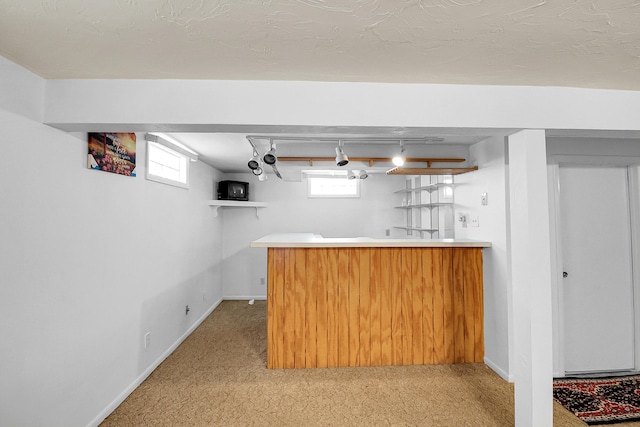 bar featuring light colored carpet, indoor bar, and baseboards