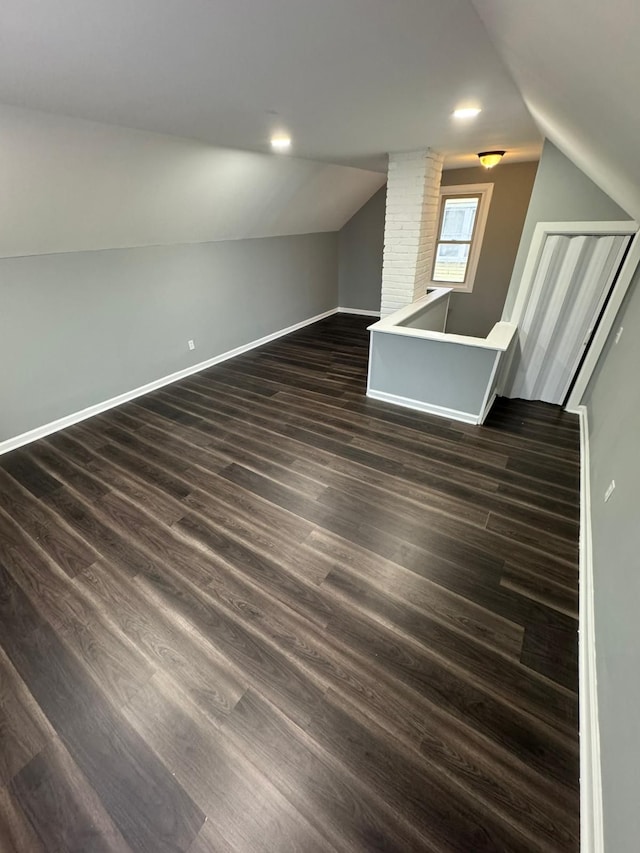 additional living space with baseboards, vaulted ceiling, and dark wood-type flooring